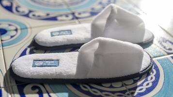 A pair of white slippers with a label on a tiled floor with a blue and white pattern.