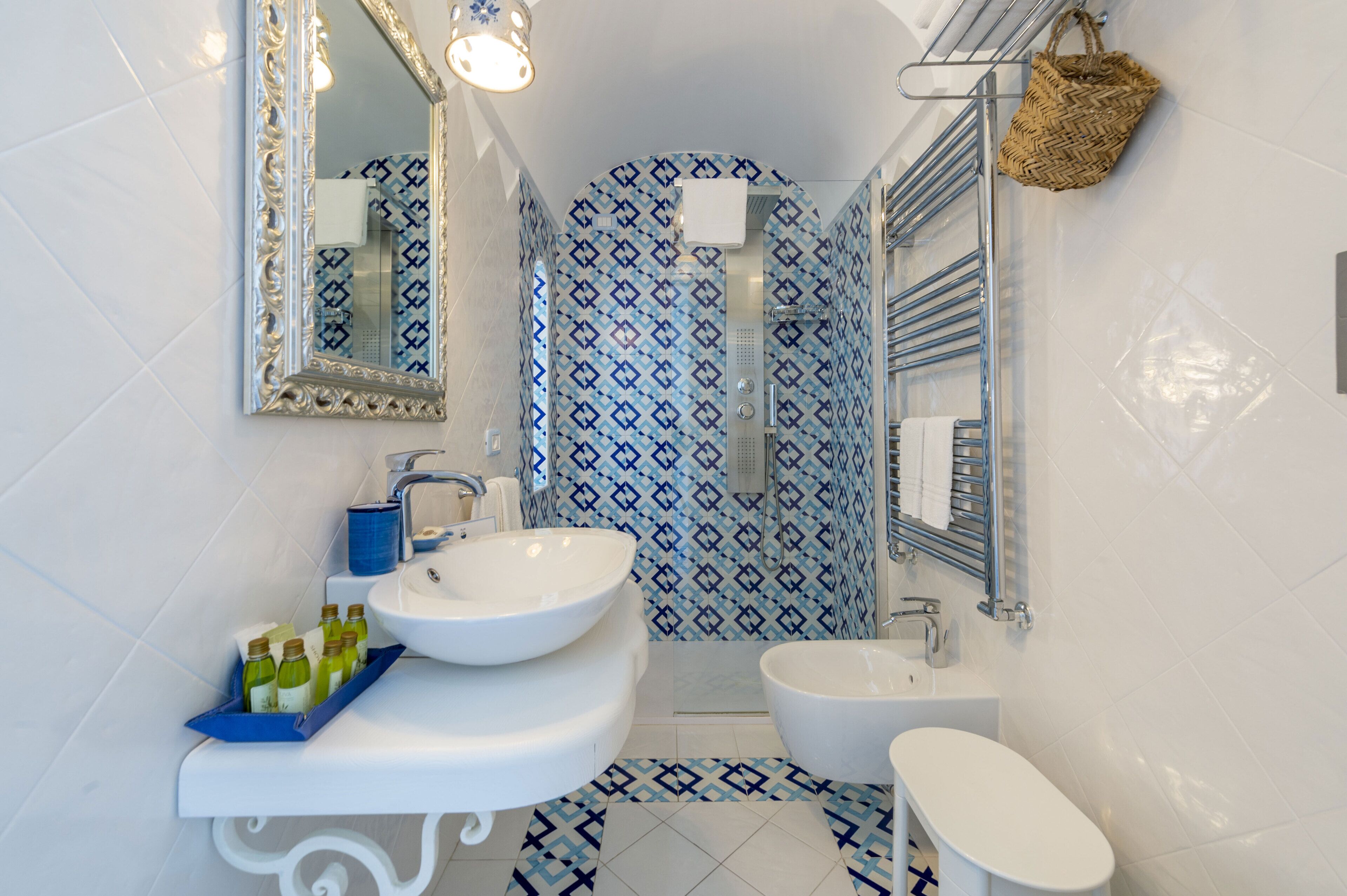 A bathroom with a double sink, a toilet, a shower, and a mirror.