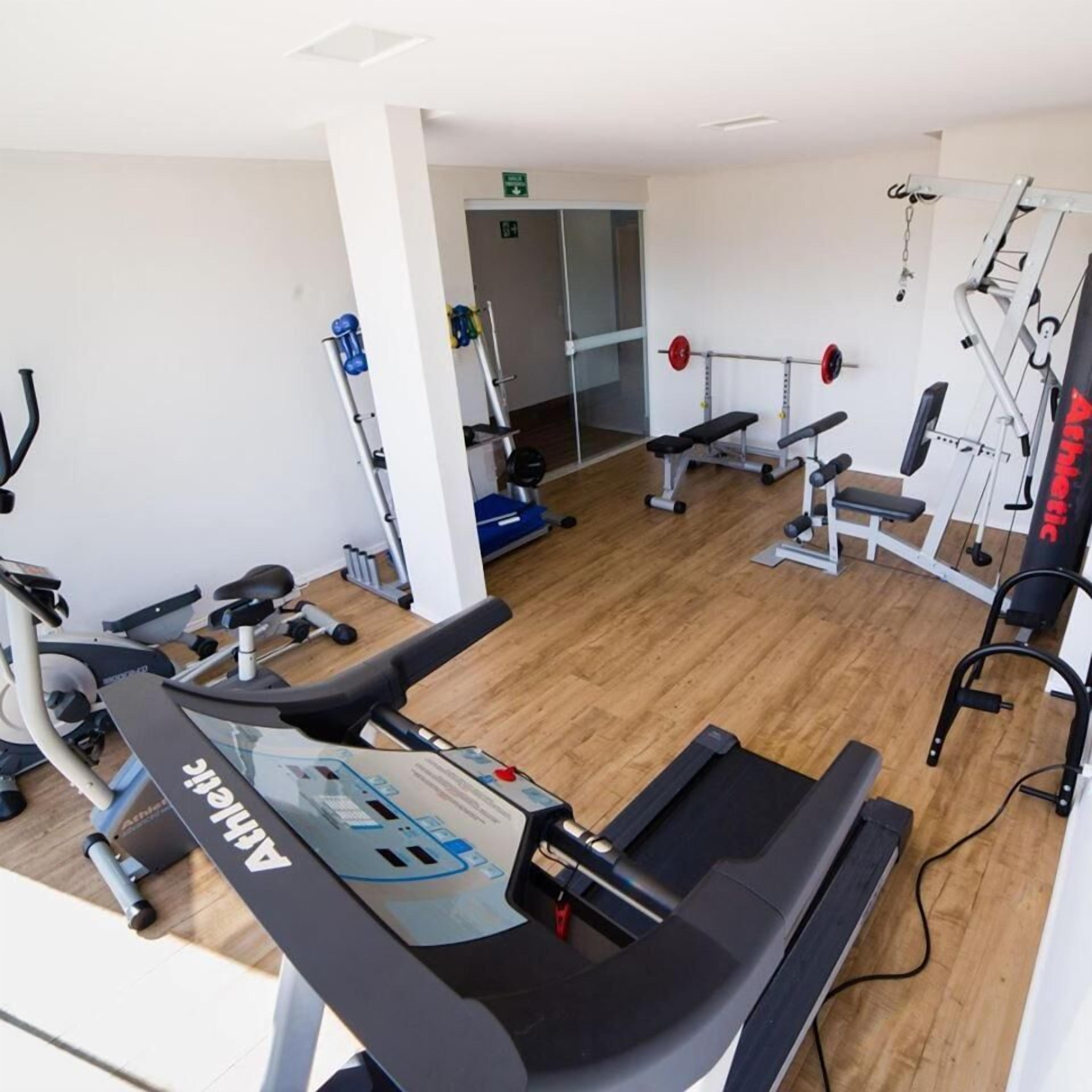 A gym with cardio equipment, weight machines, and a mirrored wall.