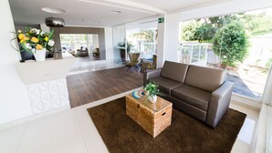 A spacious living area with a brown rug, a brown sofa, and a wicker coffee table with a plant. - Serra Madre Residence (Rio Quente)