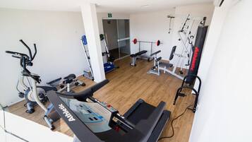 Un gimnasio con máquinas de cardio, equipo de levantamiento de pesas y un espejo grande.