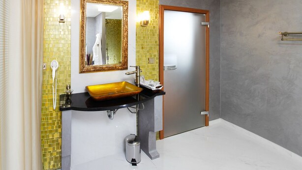 A bathroom with a black sink, yellow-tiled walls, a mirror, and a door. - Lux hotel Onyx (Svinošice)