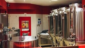 A modern kitchen with stainless steel appliances, a red accent wall, and a visible fire extinguisher. - De La Tour (Tirano)