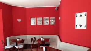 A dining area with a red wall, a black and white checkered tablecloth, and a black and white checkered table. - De La Tour (Tirano)