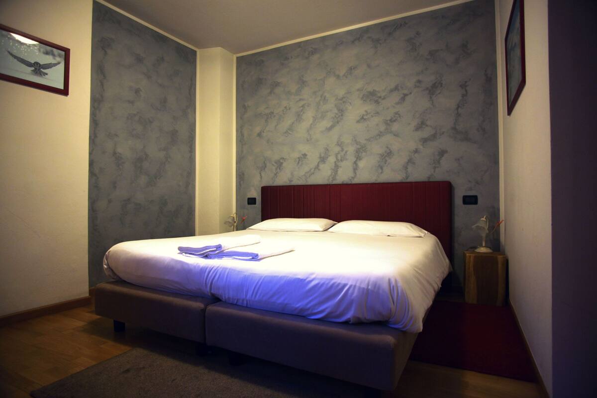 A bedroom with a bed, a nightstand, and a wall-mounted lamp.