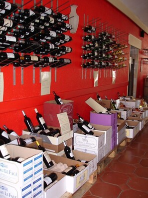Une cave à vin avec des bouteilles rangées sur des étagères et dans des caisses, dont certaines portent des étiquettes avec des noms.