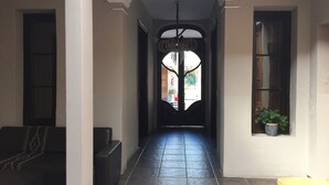 Un corridoio con pavimento in piastrelle nere, un lampadario e una panca a sinistra.