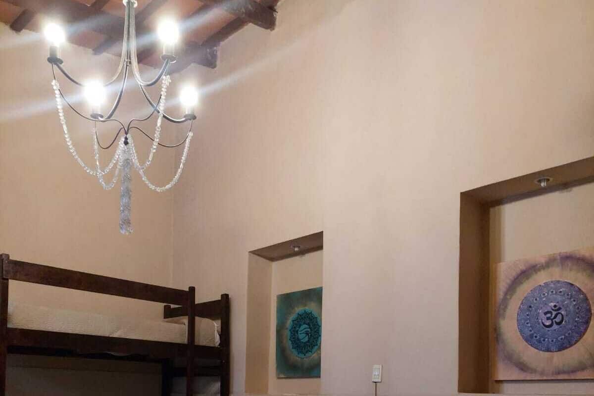 A room with three bunk beds, a chandelier, and two wall art pieces.