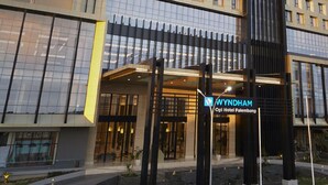 Un hôtel à la façade moderne, doté de plusieurs étages et d’une entrée imposante sur laquelle est apposée une enseigne indiquant « WYNDHAM Oli Hotel Palembang ».