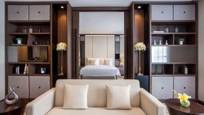 Une chambre d’hôtel moderne dotée d’un grand lit, d’un canapé et d’étagères intégrées où sont disposés des objets décoratifs.