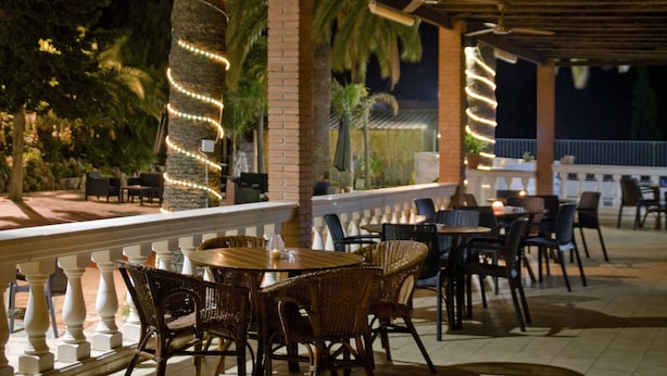 An outdoor patio area with wicker furniture, brick pillars, and string lights. - San Martin (Altafulla)