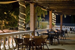 An outdoor patio area with wicker furniture, brick pillars, and string lights.