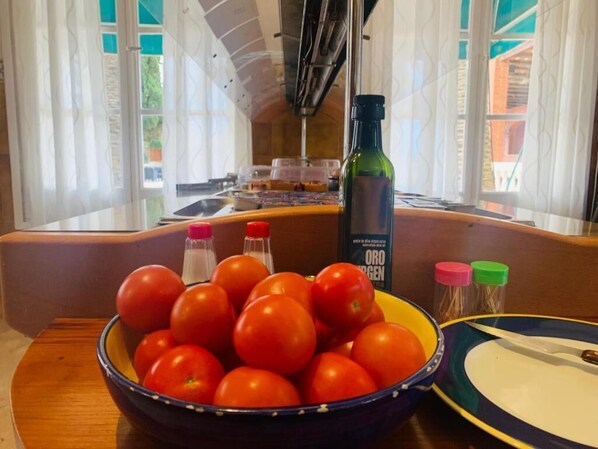 A kitchen counter with a bowl of tomatoes, a bottle of olive oil, and a book titled "Oro d'oro".
