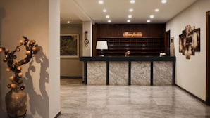 A hotel reception area with a marble counter, a clock, and framed artwork on the walls. - San Martin (Altafulla)