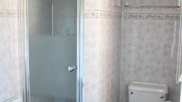 Une salle de bain avec une douche à parois de verre, des toilettes et une étagère avec des serviettes.