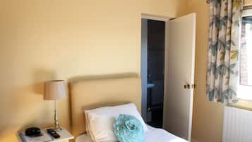 Una camera da letto con un letto, un comodino con una lampada, un telecomando e un cuscino decorativo.