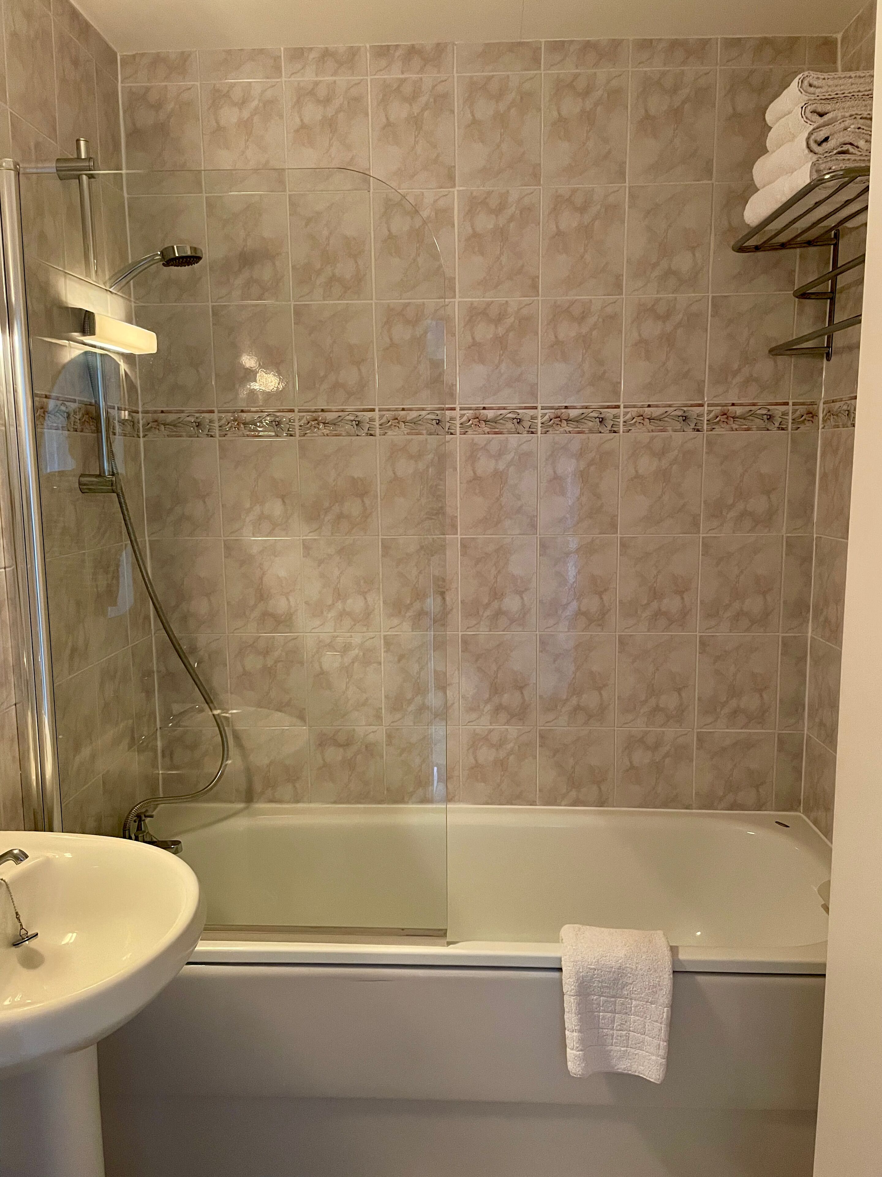 Ett badrum med en dusch som är avskärmad med glasväggar, ett vitt handfat och ett badkar.