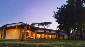 Un edificio grande con varias zonas de comedor, un área de estar al aire libre cubierta y un césped.