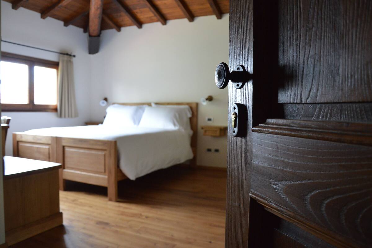 Un dormitorio con una cama y escritorio de madera, y una ventana con cortinas.