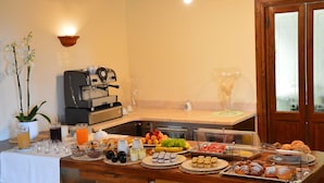 Montaje de bufé con diferentes opciones de comida, una máquina de café y una copa de vino.