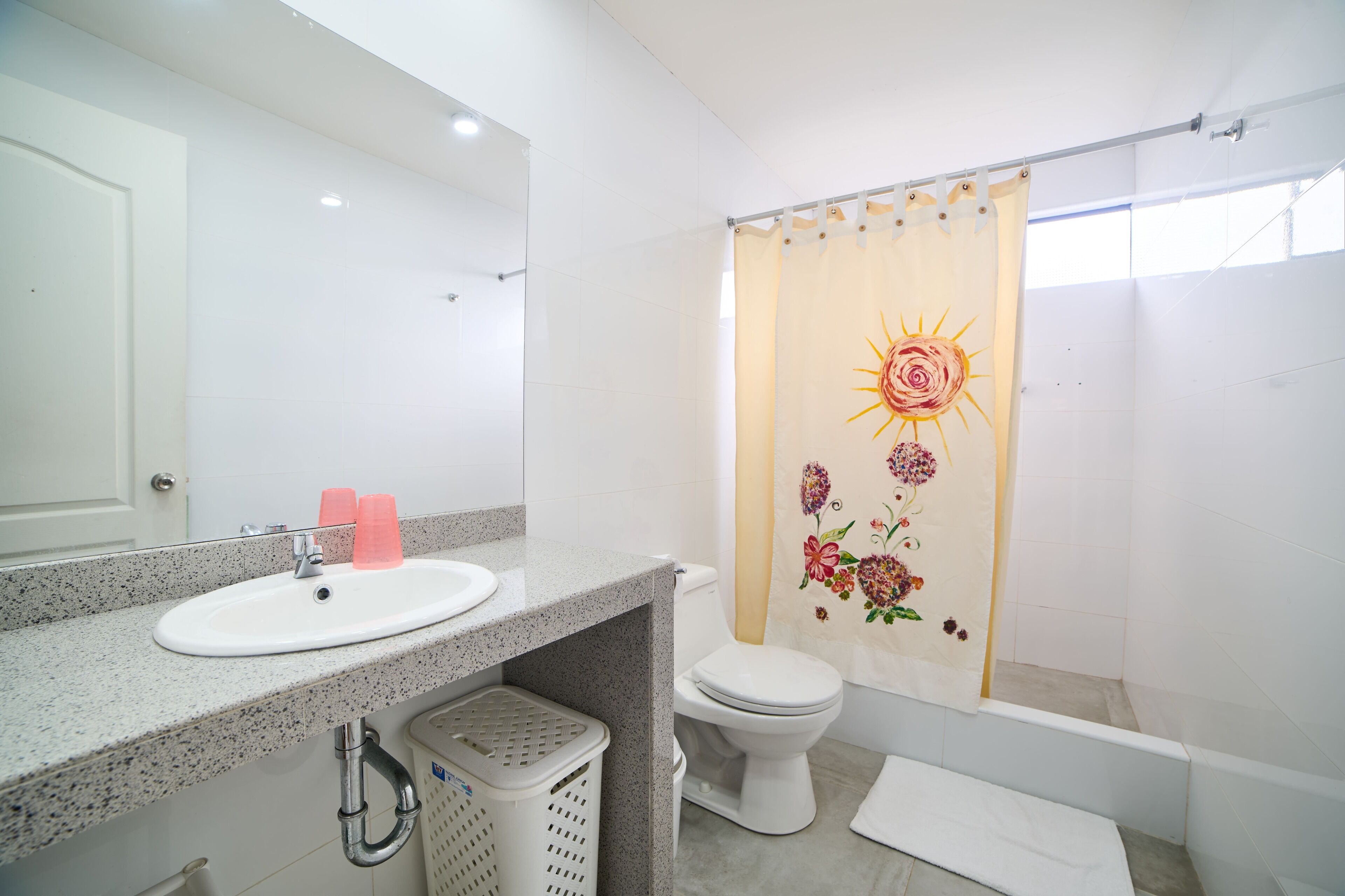 A bathroom with a white sink, a toilet, and a shower curtain with a floral design.