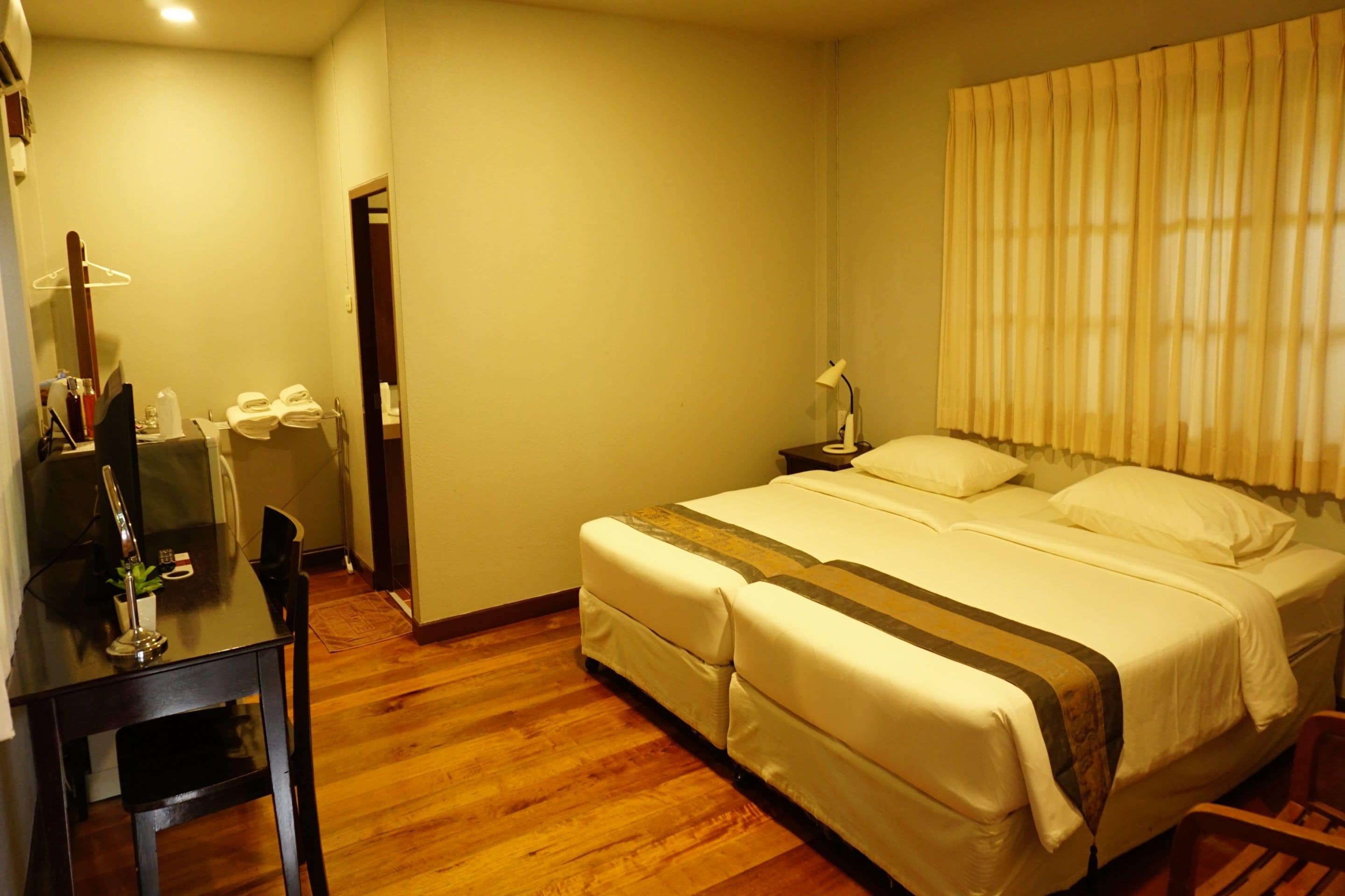 A hotel room with a bed, bedside table, lamp, and a mirror.