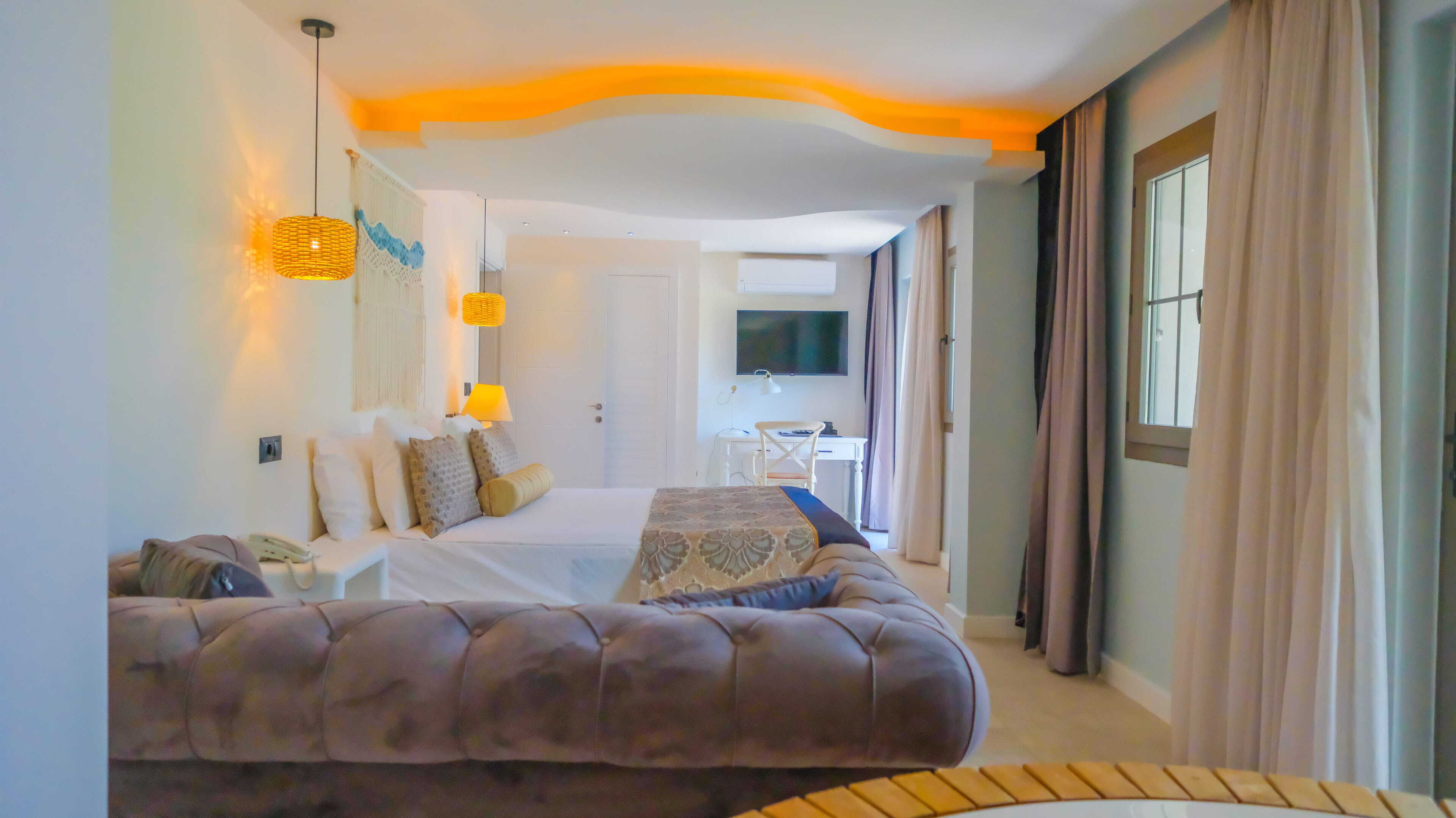 Hotellihuone, jossa on suuri sänky, työpöytä, televisio ja näkymä ulos.