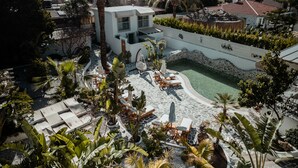 A resort with a swimming pool, lounge chairs, and tropical plants.