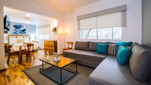 En moderne stue med sofa, sofabord og spiseplads med stole og bord.