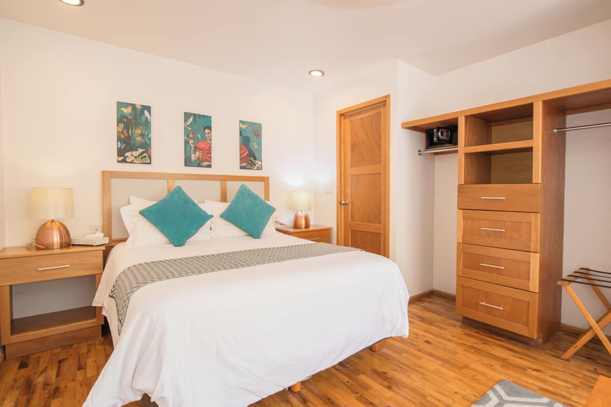 Ein Schlafzimmer mit einem Holzbett, zwei Nachttischen mit Lampen, einem Kleiderschrank und Bildern an der Wand.