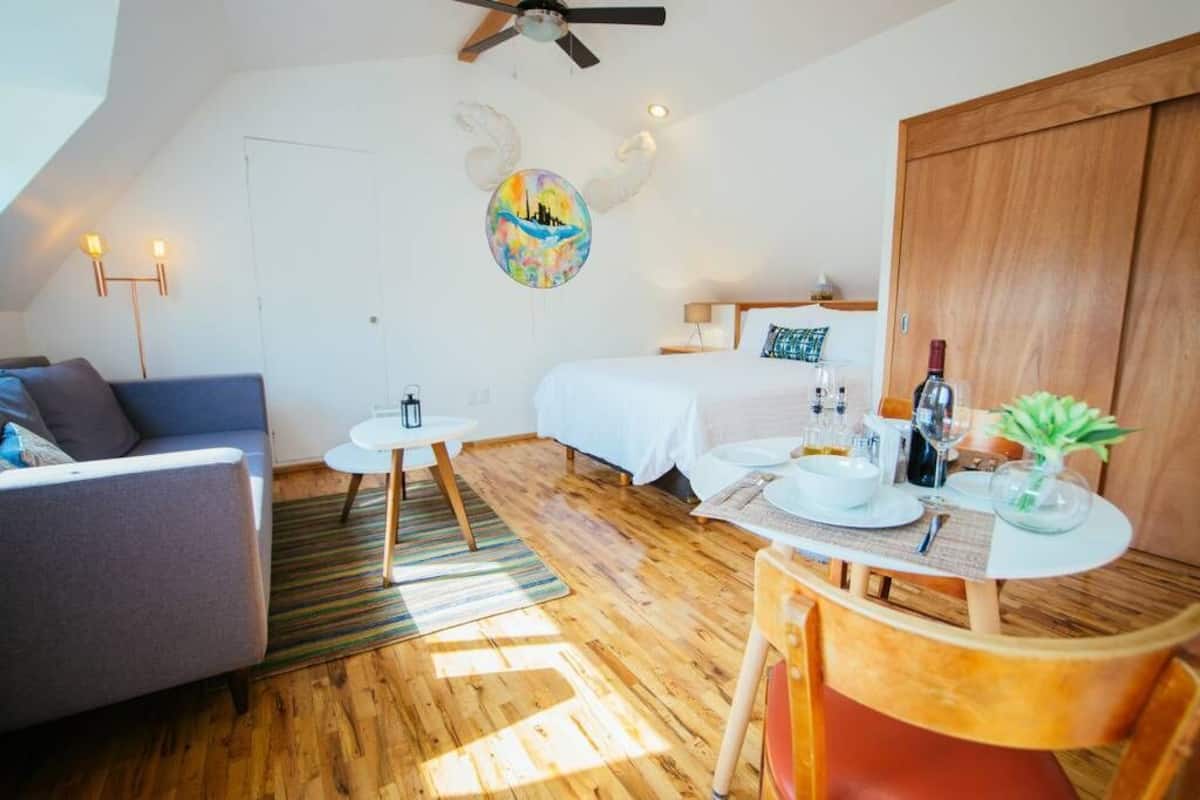 Ein modernes Schlafzimmer mit einem Bett, einem kleinen Tisch mit einer Vase und einem Sofa.