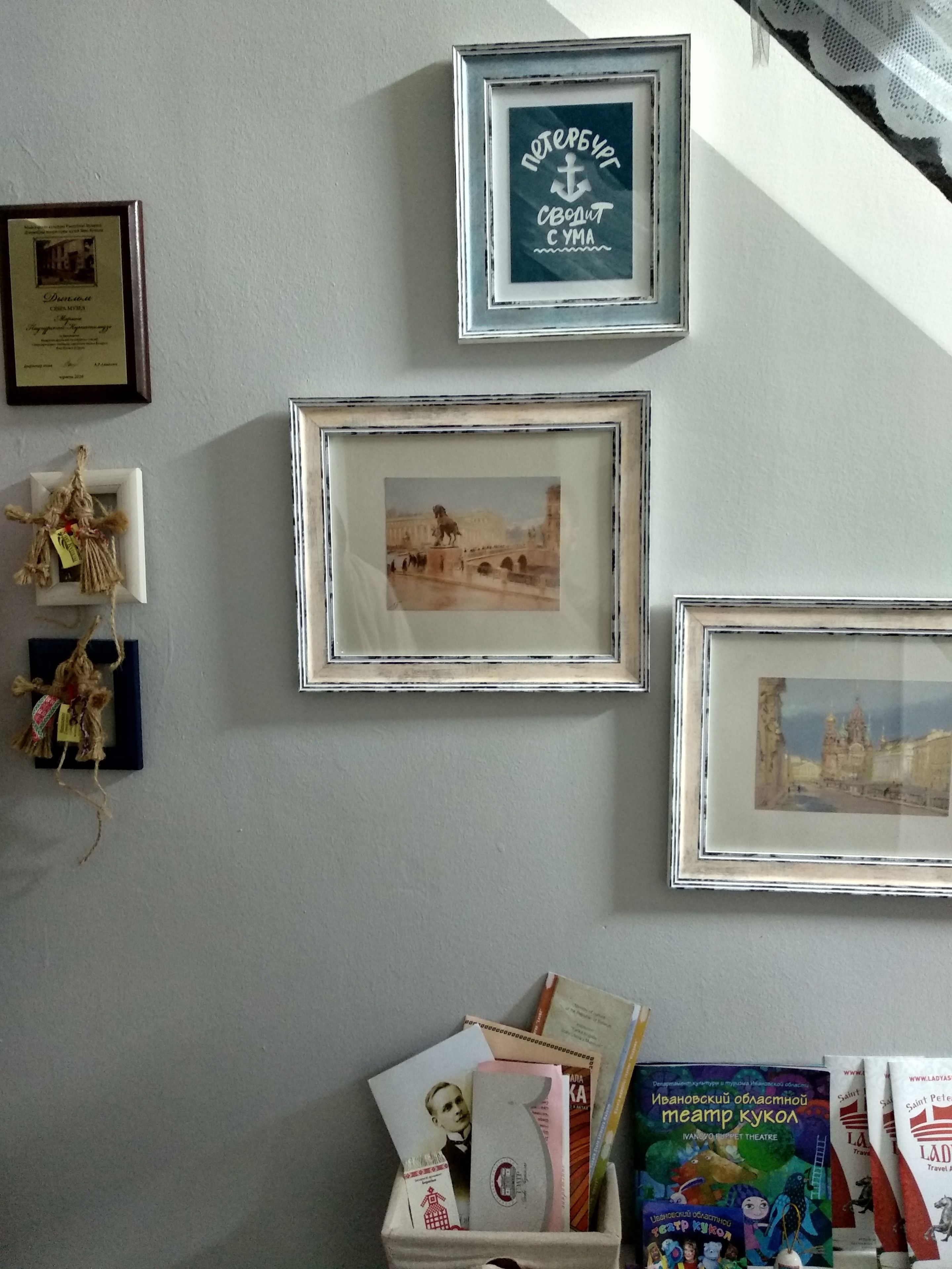 Una pared con varios cuadros enmarcados, algunos con texto y otros que muestran escenas.