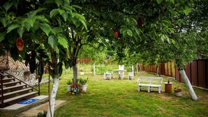 Ein Garten mit einer weißen Bank, einem kleinen Tisch und Blumentöpfen.