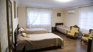A hotel room with two beds, a chair, a bedside table, and a mirror.