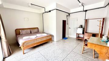 Een kamer met een bed, een bureau, een stoel, een spiegel en een deur.