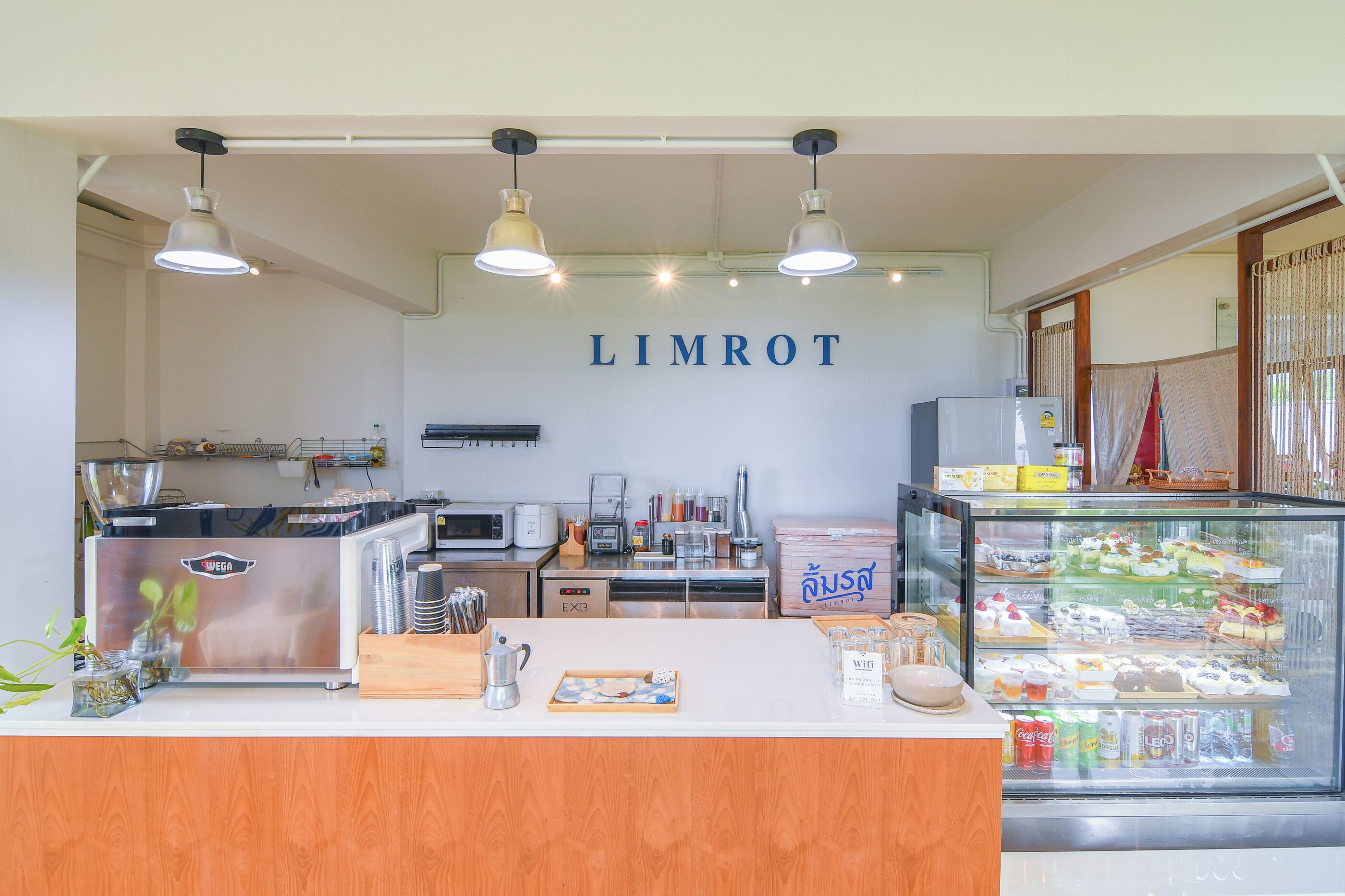 A café interior with a counter, coffee machines, a display case with pastries, and a sign reading "LIMROT".