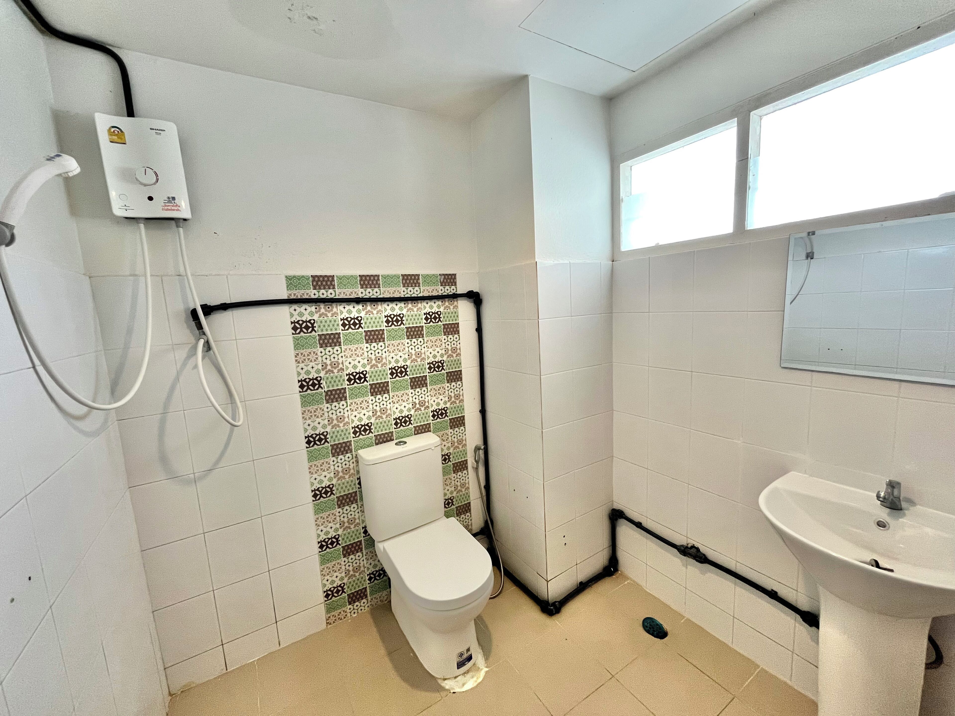 Ein kleines, schlichtes Badezimmer mit Toilette, Waschbecken und Dusche.