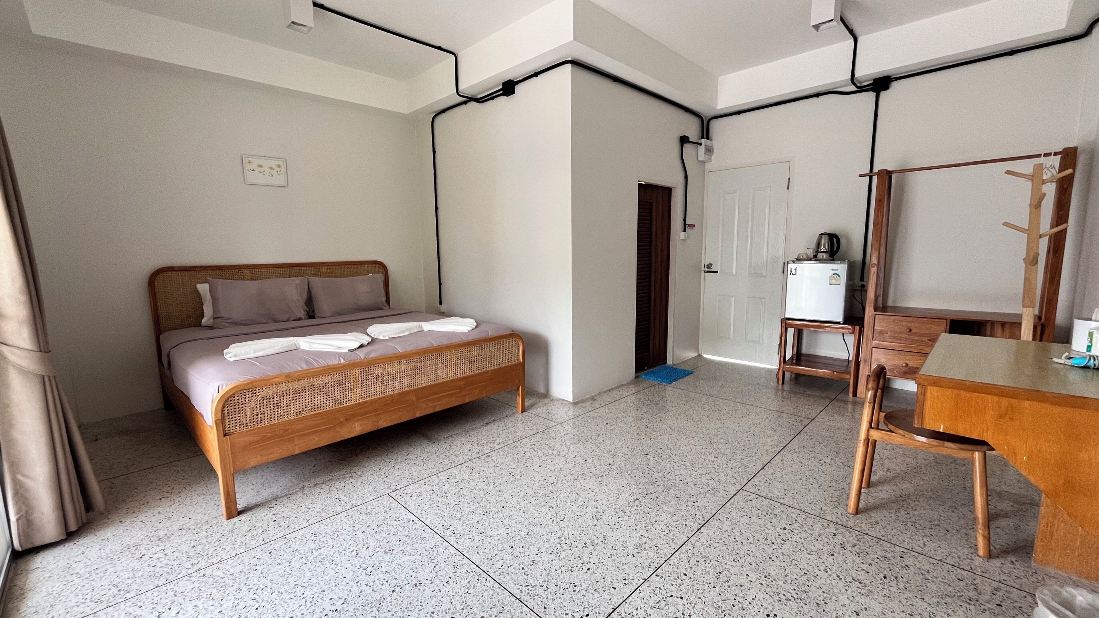 A room with a bed, a table, a chair, and a refrigerator.