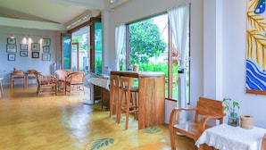 Ein geräumiger Raum mit Holzmöbeln, einem großen Fenster und Blick ins Grüne.