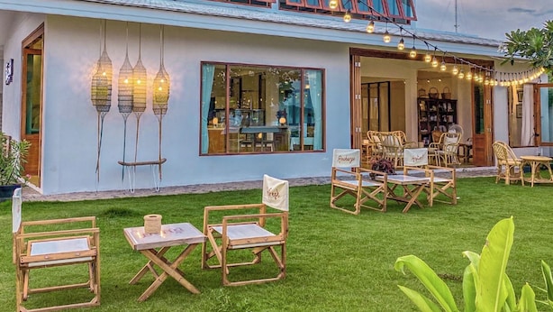 Ein zweistöckiges Haus mit Balkon, Sitzgelegenheit im Freien und Lichterketten.