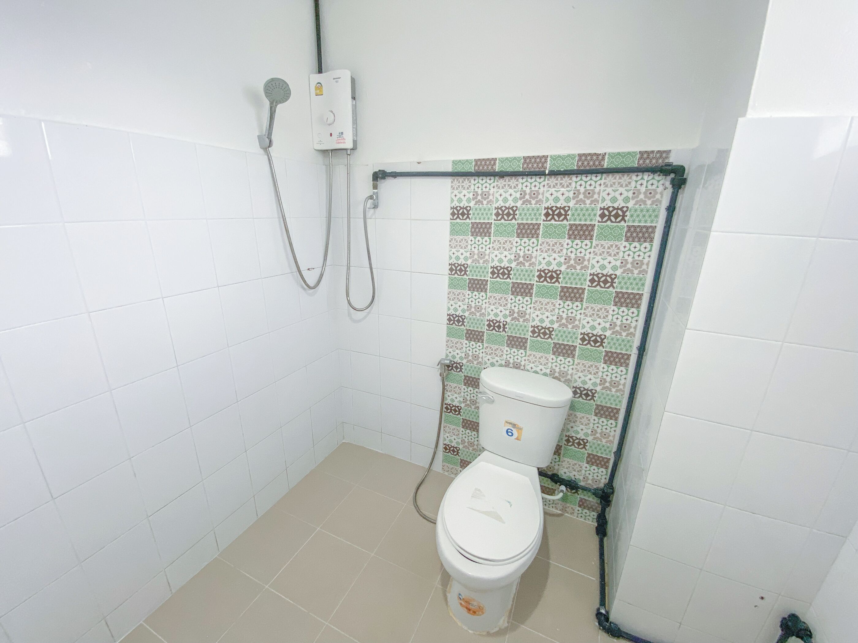 Ein kleines Badezimmer mit Fliesen, einer Toilette, einer Dusche und einem Wandheizkörper.
