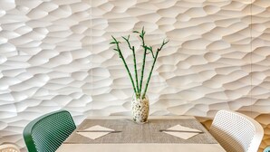 A dining table with a vase of bamboo and pebbles, set against a textured wall. - Hostal La Fonda (Cadaqués)