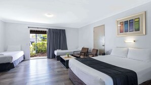 A hotel room with two single beds, a large bed, a desk with a chair, and a view of the outdoors. - Comfort Inn North Brisbane (Carseldine)