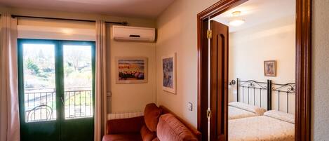 A room with a sofa, a bed, and a door leading to a balcony.