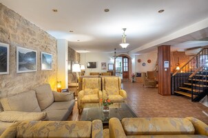 Amplia sala de estar con pared de piedra, un sofá, sillones, una mesa de centro y una escalera.