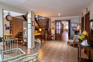 Un salón amplio con una escalera, una mesa de comedor con sillas y un jarrón decorativo sobre una mesita auxiliar.