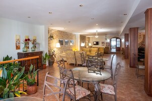 Un comedor amplio con una pared de acento de piedra, varias opciones de asientos que incluyen una mesa redonda y sillas, y una escalera que conduce a un nivel superior.