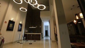 A modern lobby with a reception desk, a patterned wall, and a ceiling with circular light fixtures. - Brii hotel (Araguaina)