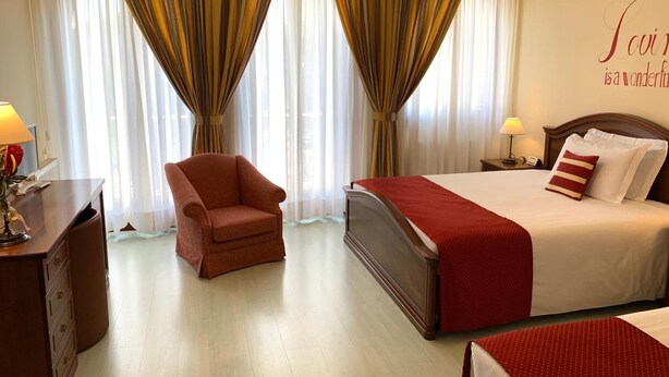 A hotel room with a bed, a chair, a desk, and curtains. - Albergo Italia (Fossalta di Piave)
