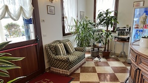 A cozy lobby with a checkered floor, a patterned sofa, potted plants, and a coffee machine. - Albergo Italia (Fossalta di Piave)